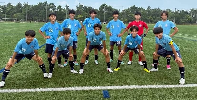 中学生年代の選手たちがグラウンドでストレッチをする様子